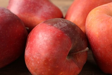 Many rotten red apples on wooden table, closeup