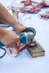 a man is cutting the bones of a cow or sheep with a grinding machine