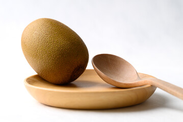 Fresh kiwi fruit with wooden plate and spoon on white background, Healthy eating