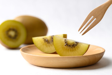 Sliced sungold kiwi fruit on wooden plate with fork ready to eating