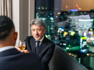 都市の夜景を背景に乾杯する多国籍ビジネスパーソン