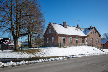 Old Roinge school building with snow-covered roof and winter landscape in Haessleholm, Sweden
