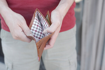 A man holding empty wallet, high cost of living, financial crisis, inflation, stagflation concept