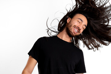 Young Latin man flipping his long hair and smiling placidly with his braces on white background
