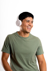 Young Latin man laughing carefree on white background with headset over his ears