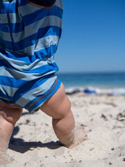 Baby learning to walk on a sunny sandy beach