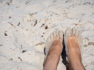 Sandy bare feet resting on a bright sunny beach