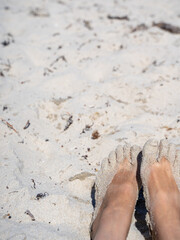 Sandy bare feet resting on a bright sunny beach