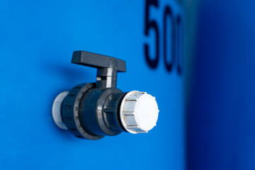 "close-up of a plastic valve attached to a blue water tank, featuring industrial design and functionality. ideal for themes of plumbing, engineering, or water management."