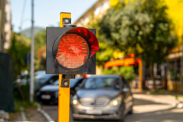 A red traffic signal, halting vehicles on a city street. cars wait at the intersection, emphasizing urban traffic flow and transportation themes.