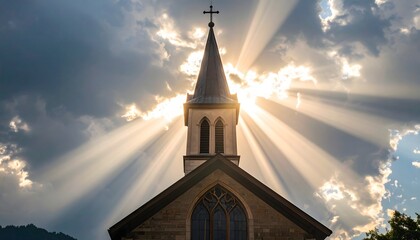 A church steeple silhouetted against the sun's rays piercing through clouds. A Gothic-style church steeple rises against a backdrop of dramatic clouds with sunlight streaming through
