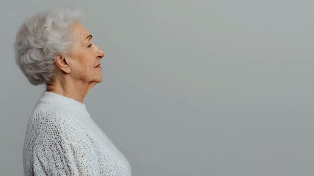Older woman looks up with hope and reflection. Profile of a senior female with gray hair for healthy aging, Alzheimer awareness