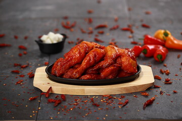 Korean Yangnyeom Chicken with sweet and spicy glaze, served on a wooden plate with pickled radish and vegetables. A signature K-Food enjoyed for its bold flavor and crispy texture.