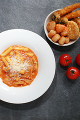 Korean Rose Tteokbokki, a creamy spicy rice cake dish topped with cheese, served with assorted fried snacks. A popular K-Food fusion dish enjoyed for its rich flavor and texture.