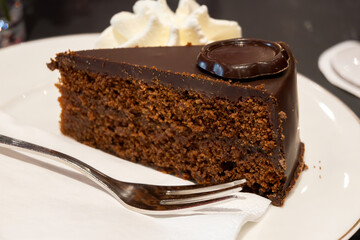 Piece of famous Sachertorte chocolate cake with apricot jam of Austrian origin served with whipped...