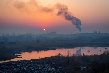 Fototapeta premium Smogshrouded sunset over polluted industrial landscape