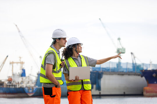 Port Engineers Discussing Logistics at a Shipping Yard, Young Industrial Workers Overseeing Operations at a Commercial Dock, Team of Maritime Professionals Planning at a Harbor