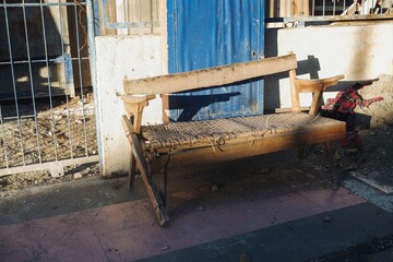 A close-up photo of a weathered and broken vintage wooden chair left on the side of a road,...