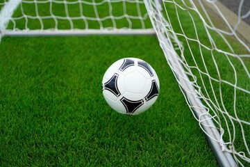 Soccer ball approaching goal net green field