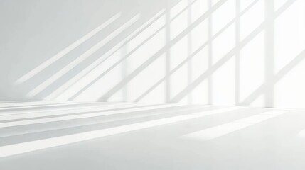 Obraz premium Bright minimalistic white room flooded with natural sunlight casting long geometric shadows from windows onto the floor and walls, evoking calm and spacious atmosphere