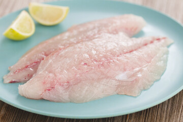Fresh raw jack fish fillets on blue plate with lemon (Selective Focus, Focus  on the front of the fish)