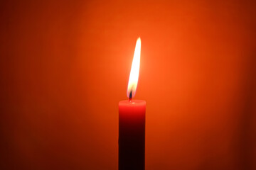 Close-up of a burning candle on a orange background