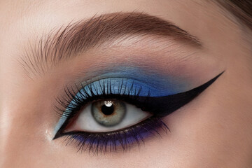 Fototapeta premium A close-up beauty shot of an eye makeup look featuring a dramatic winged eyeliner in black and metallic blue.