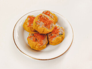Yellow dimsum or Siomay chicken and shrimp variance with carrot above, isolated in white background.