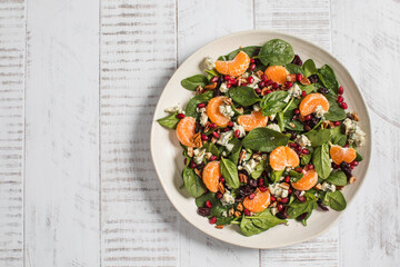 Fresh spinach and citrus salad with pomegranate and blue cheese on rustic white wood. Copy space