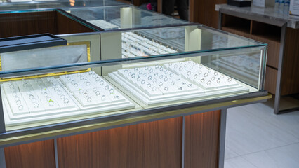 Close-up of luxury rings displayed in a glass jewelry case inside a modern jewelry store, showcasing various diamond and gemstone designs in an elegant presentation.