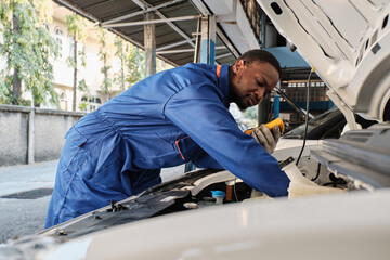EV car check, Black male mechanic worker inspects and maintains service of electric engine and...
