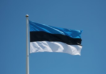 Estonian flag waving proudly in the wind against a clear blue sky
