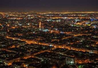 Obraz premium Night cityscape with illuminated buildings and streets from an aerial view