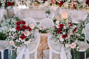 Romantic wedding floral arrangement on chairs at ceremony venue decor