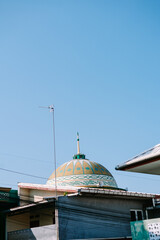 Mosque Dome Amidst Rooftops and Clear Sky in Urban Neighborhood