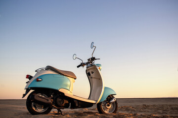 A bright blue retro scooter stands out in the golden desert, symbolizing adventure, simplicity, and...