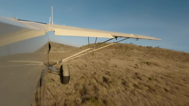 Hyperlapse of aerial wide of small plane flying over savannah with scattered shrubs, rocks and hills in a sunny morning in Kenya