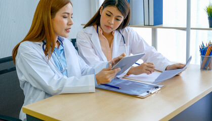 Two asian women doctors discuss meeting doctor's office medical clinic using laptop consulting...