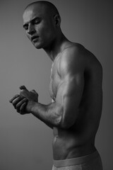Athletic man in a thoughtful pose, showcasing his strong physique and intense expression. The image...