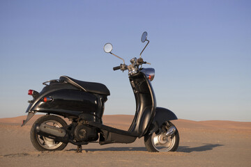 A black retro scooter parked in the vast desert, symbolizing freedom, timeless design, and minimalism. Ideal for editorial, road trip, and vintage motorbike concepts.
