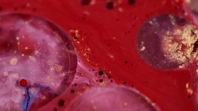 Paint blob. Shimmering liquid. Defocused sparkling red color ink fluid moving on glittering abstract blurred particles background.