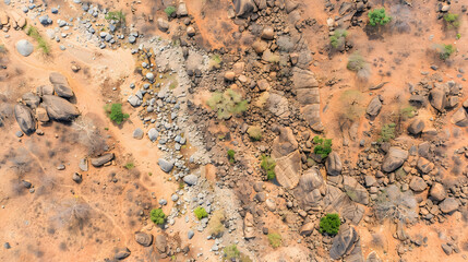 An aerial shot reveals a dried-up riverbed amongst scattered rocks sparse vegetation a sun-baked, arid landscape.