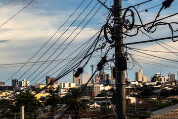 Tangled wires on a utility pole against a cityscape. Illustrates urban infrastructure challenges...