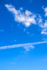 Vibrant blue sky with white clouds and contrail. Ideal for weather, travel, environment, or...
