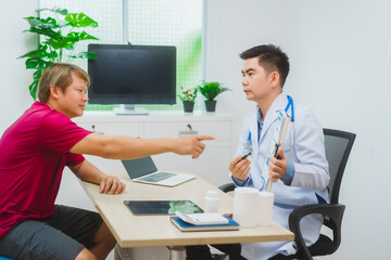 An experienced Asian male doctor consults with a male patient in a red shirt about men's health...