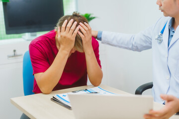 An experienced Asian male doctor consults with a male patient in a red shirt about men's health concerns. He explains a medical form, providing expert advice on urology and related health conditions