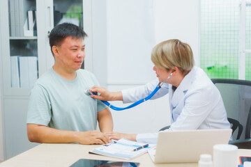 Asian male doctor specializing in cardiology explains heart disease to a patient using a heart...