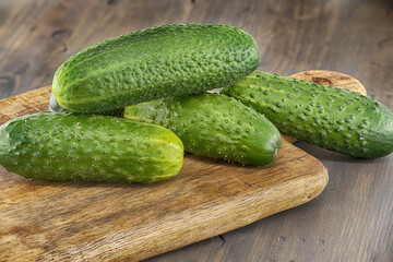 Fresh cucumbers lying on wooden cutting board