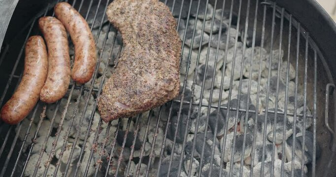steak an sausages cooking on a charcoal grill
