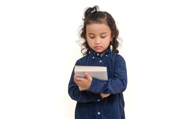 A smart little Asian girl looking at the title and picture on the cover of a book